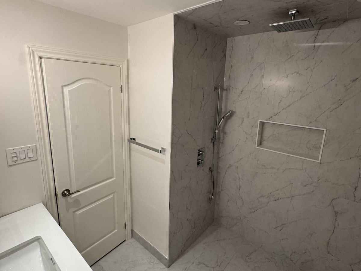 Marble-look porcelain walk-in shower with a recessed niche